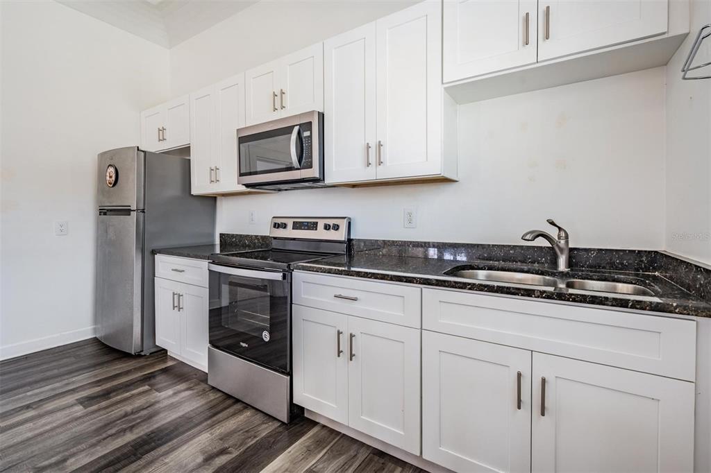 2319 West Aileen Street Tampa, FL 33607 - Photo 18 of 26 a kitchen with stainless steel appliances granite countertop white cabinets stove a sink and dishwasher