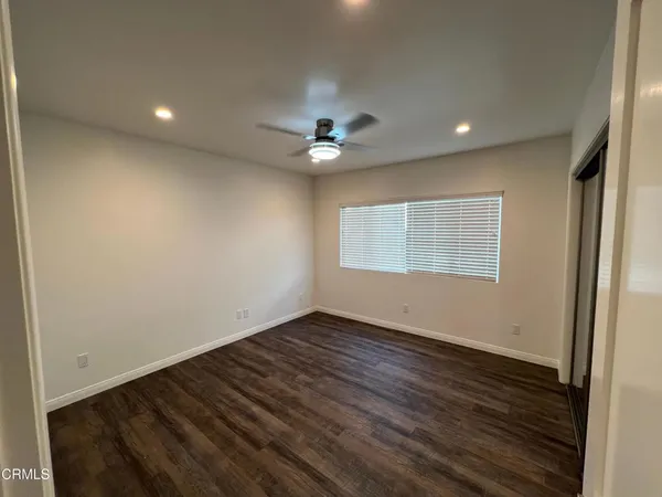 an empty room with wooden floor and chandelier fan