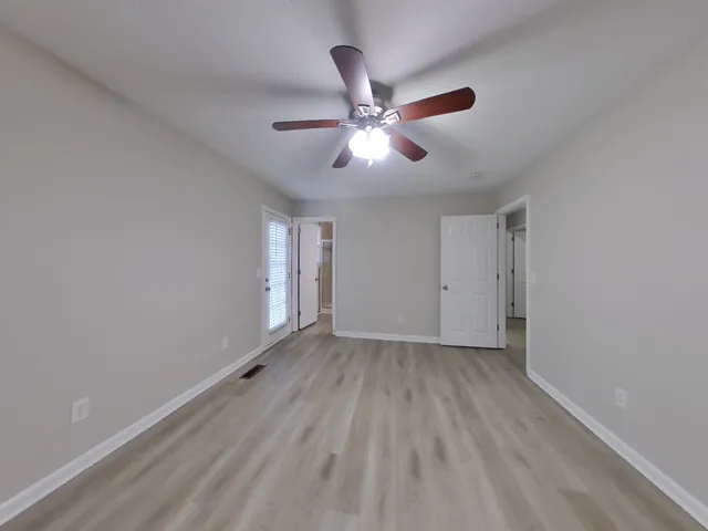 a view of an empty room with window and a ceiling fan