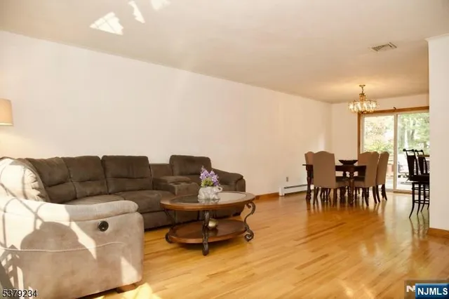 a living room with furniture and a dining table with wooden floor