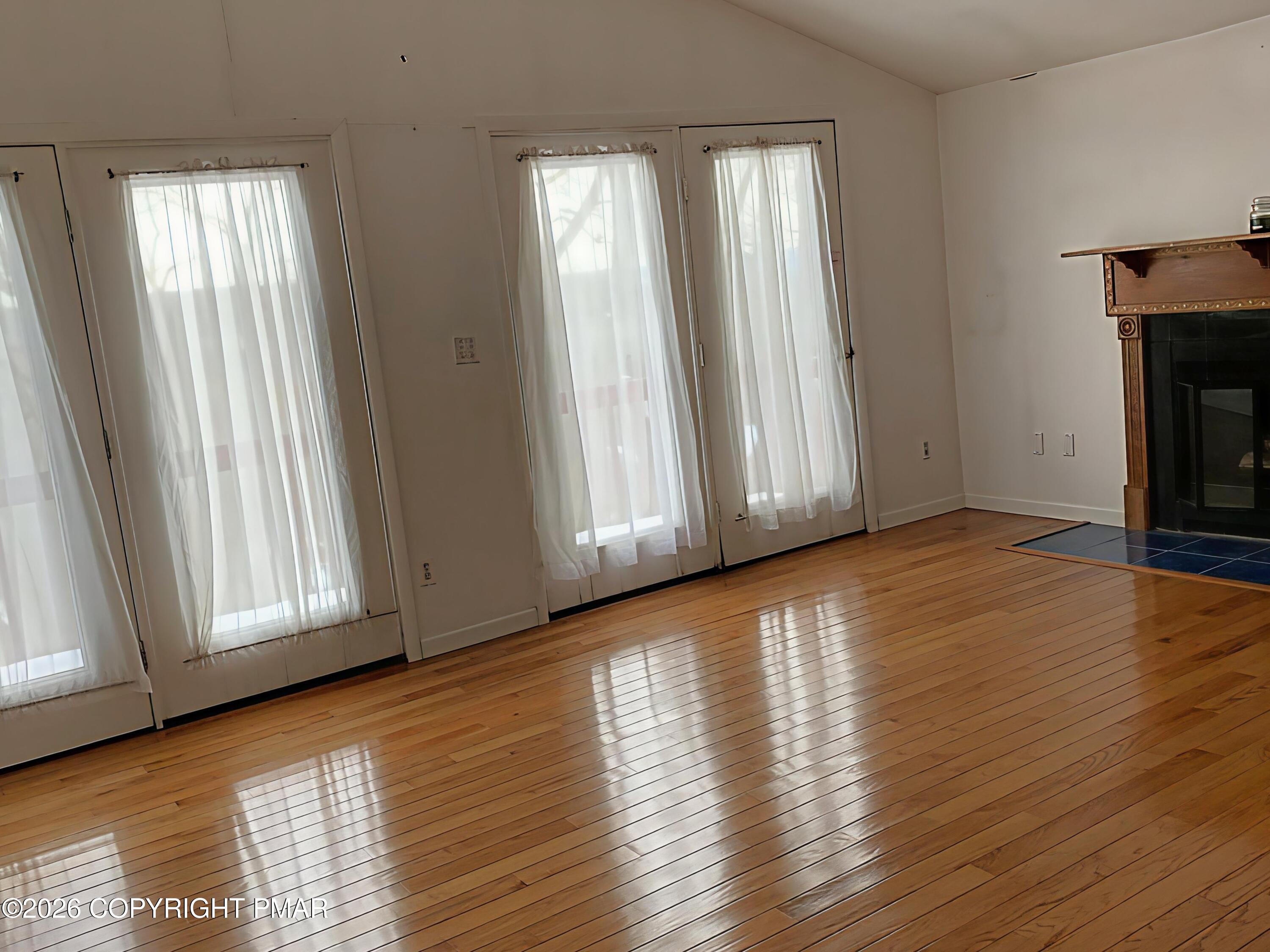 124 Saunders Drive Bushkill, PA 18324 - Photo 12 of 43 an empty room with wooden floor and windows with curtains view