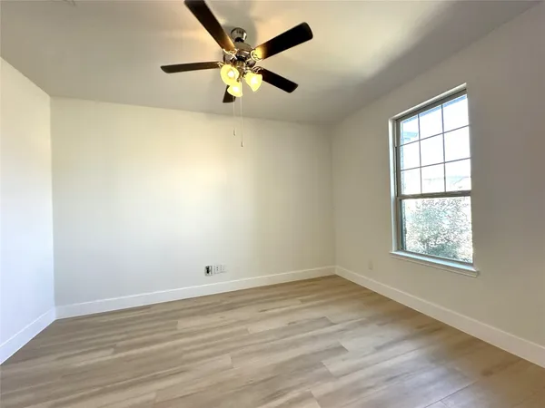 an empty room with a window and a ceiling fan