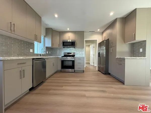 a kitchen with stainless steel appliances granite countertop a stove top oven a sink and a refrigerator