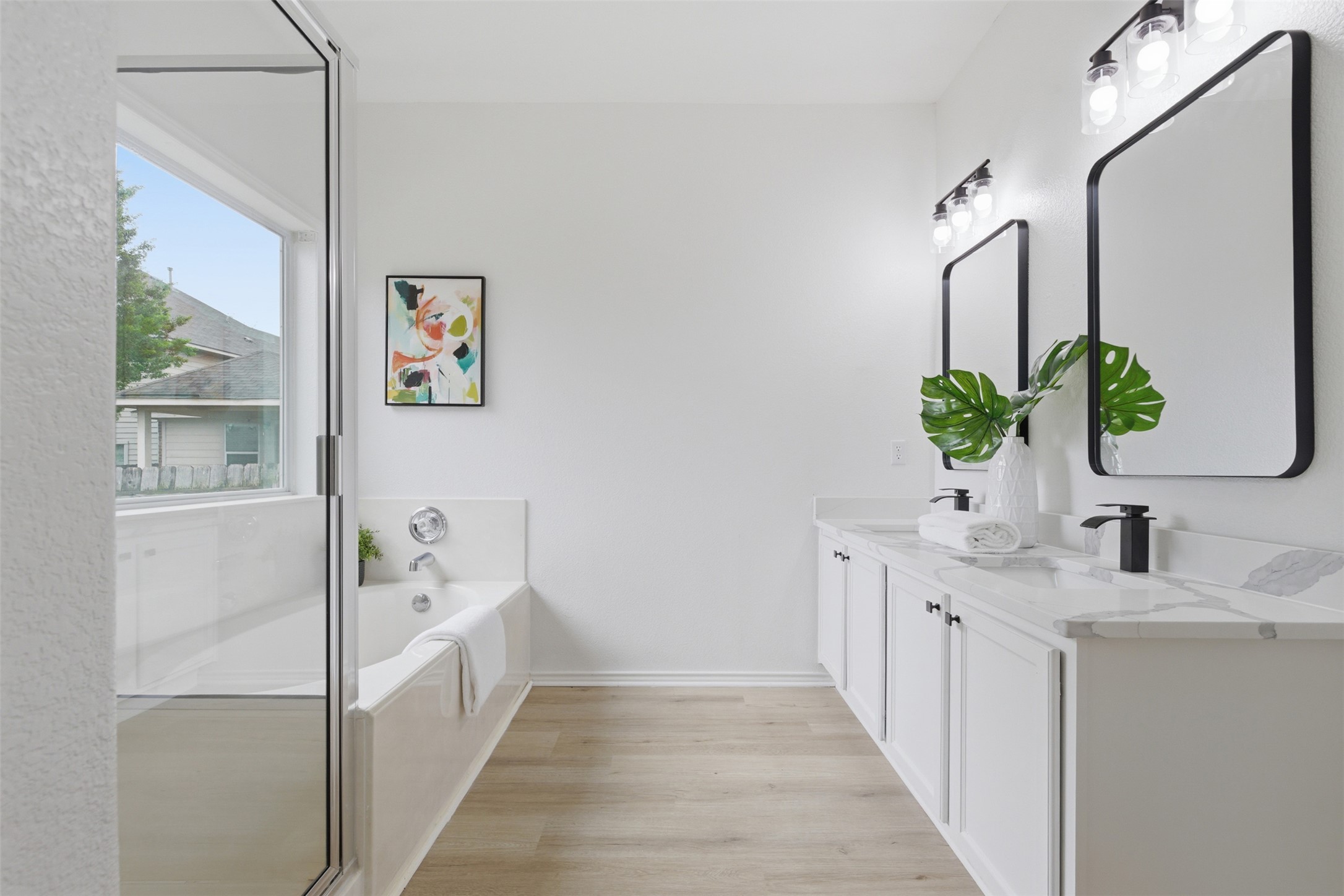461 Hot Spring Valley Buda, TX 78610 - Photo 15 of 25 Bathroom featuring a spacious soaking tub, a shower with a glass enclosure, and a double vanity with two rectangular mirrors and black fixtures