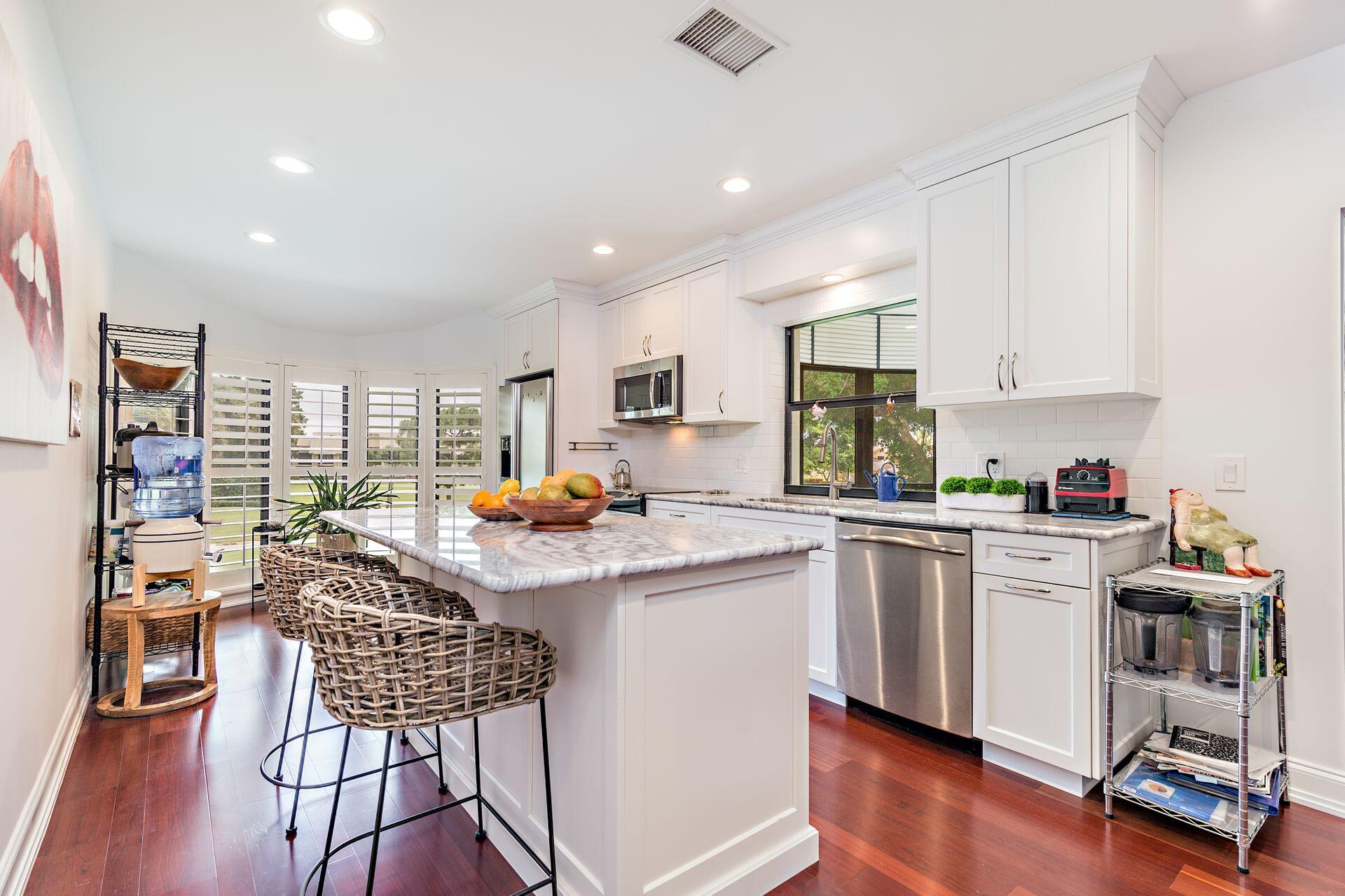 17138 Waterbend Drive, Unit 216 Jupiter, FL 33477 - Photo 7 of 20 a kitchen with stainless steel appliances granite countertop a stove top oven a sink a dining table and chairs with wooden floor