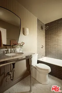 a bathroom with a sink a toilet and a large mirror