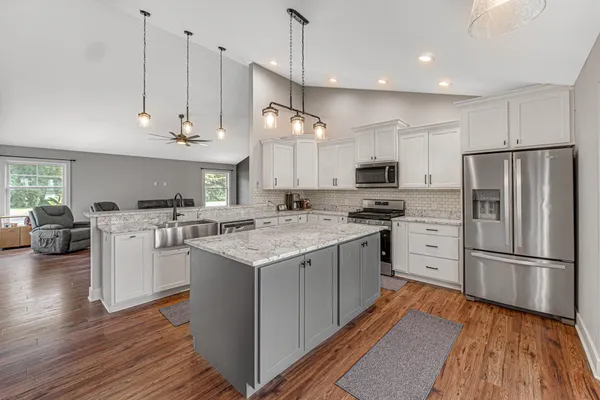a kitchen with stainless steel appliances granite countertop a refrigerator a stove top oven a sink dishwasher and a refrigerator with wooden floor