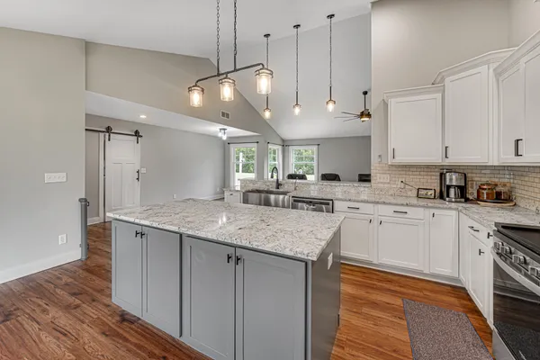 a kitchen with stainless steel appliances granite countertop a sink a stove and a refrigerator
