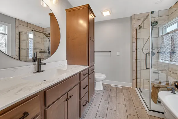 a bathroom with a sink a toilet a mirror and shower