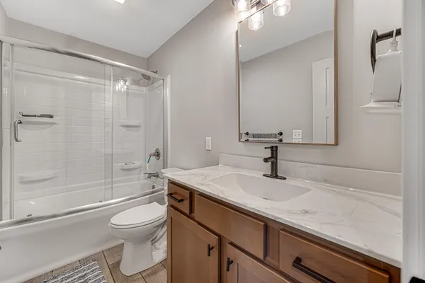 a bathroom with a granite countertop sink a toilet and shower