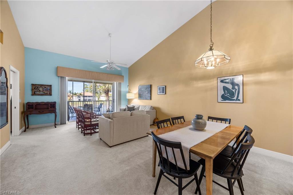 290 Robin Hood Circle, Unit 201 Naples, FL 34104 - Photo 5 of 34 a dining room with wooden floor a chandelier a wooden table and chairs