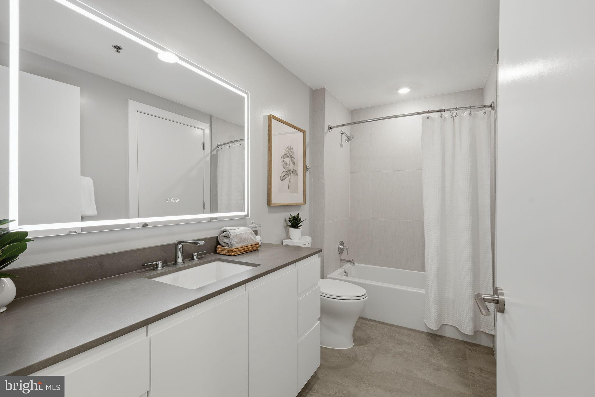 950 3rd Street Northwest, Unit 1009 Washington, DC 20001 - Photo 29 of 32 a bathroom with a double vanity sink toilet mirror and bathtub