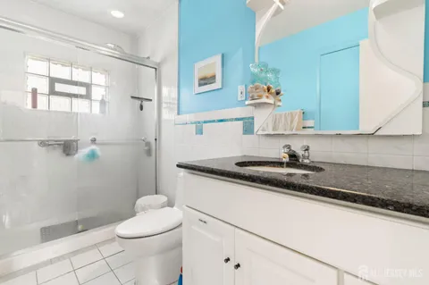 a bathroom with a granite countertop sink a toilet a mirror and shower