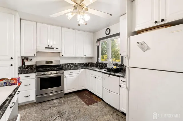 a kitchen with granite countertop white cabinets and white appliances