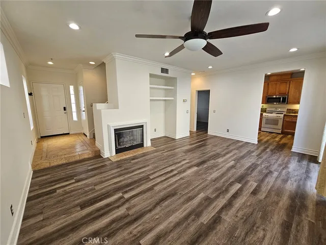 a view of a livingroom with a fireplace a ceiling fan and wooden floor