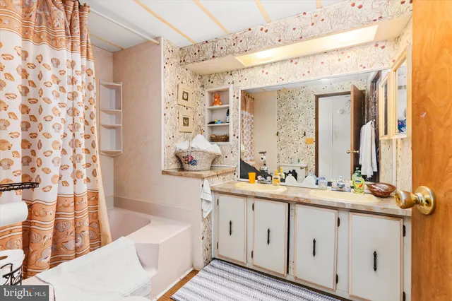 a bathroom with a double vanity sink a mirror a bathtub and shower