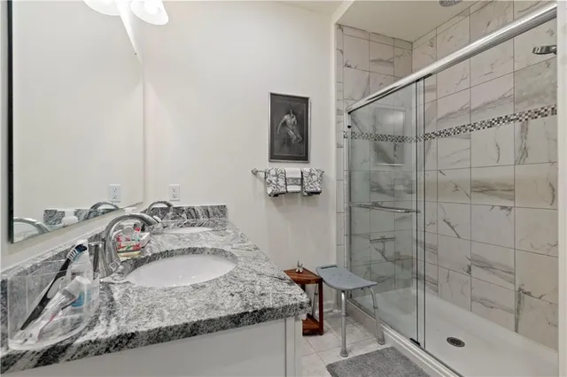 a bathroom with a granite countertop sink a mirror and shower