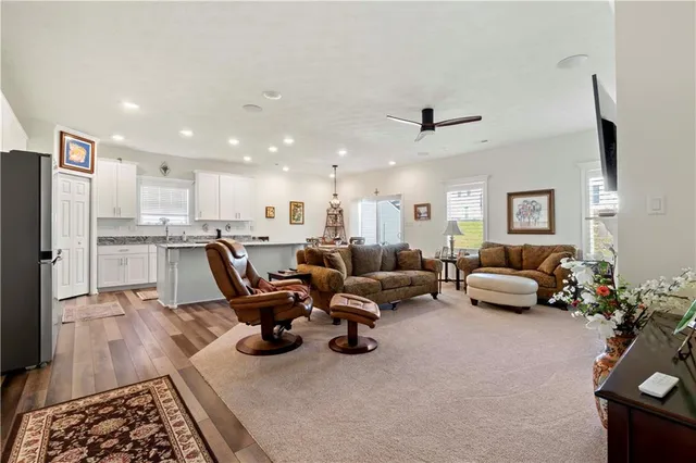 a living room with furniture kitchen view and a wooden floor