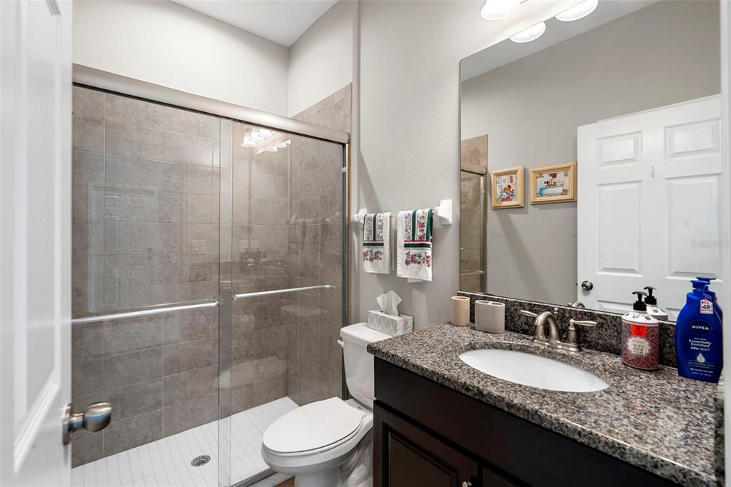 18565 Obregan Drive Spring Hill, FL 34610 - Photo 34 of 70 a bathroom with a granite countertop sink toilet a mirror and shower