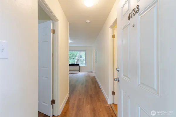 a view of a hallway with wooden floor and a living room
