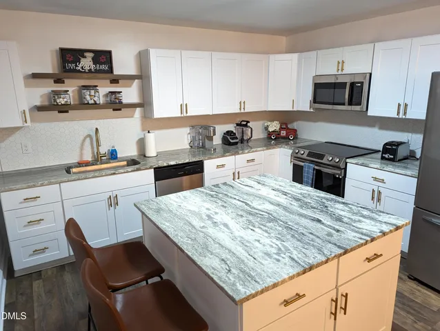 a kitchen with granite countertop white cabinets sink and stainless steel appliances