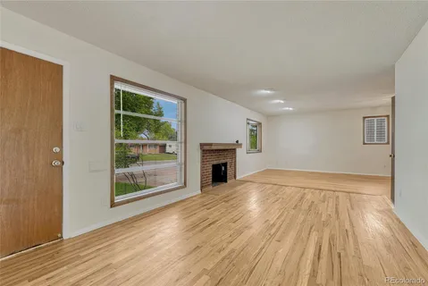 a view of empty room with wooden floor and fireplace