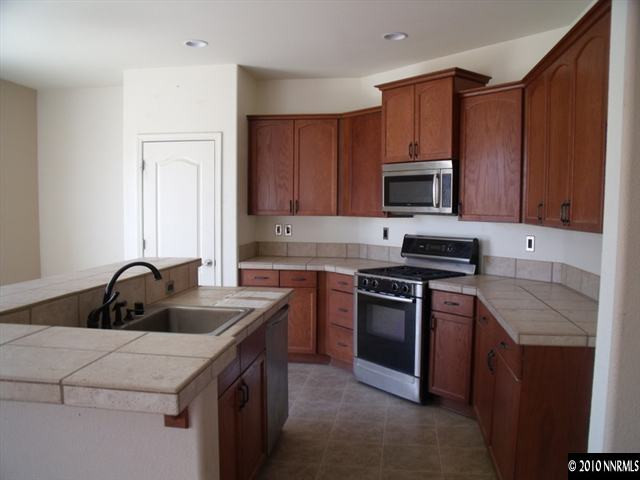 1327 Rouge River Road Fernley, NV 89408 - Photo 3 of 9 a kitchen with a sink and a stove top oven with wooden cabinets