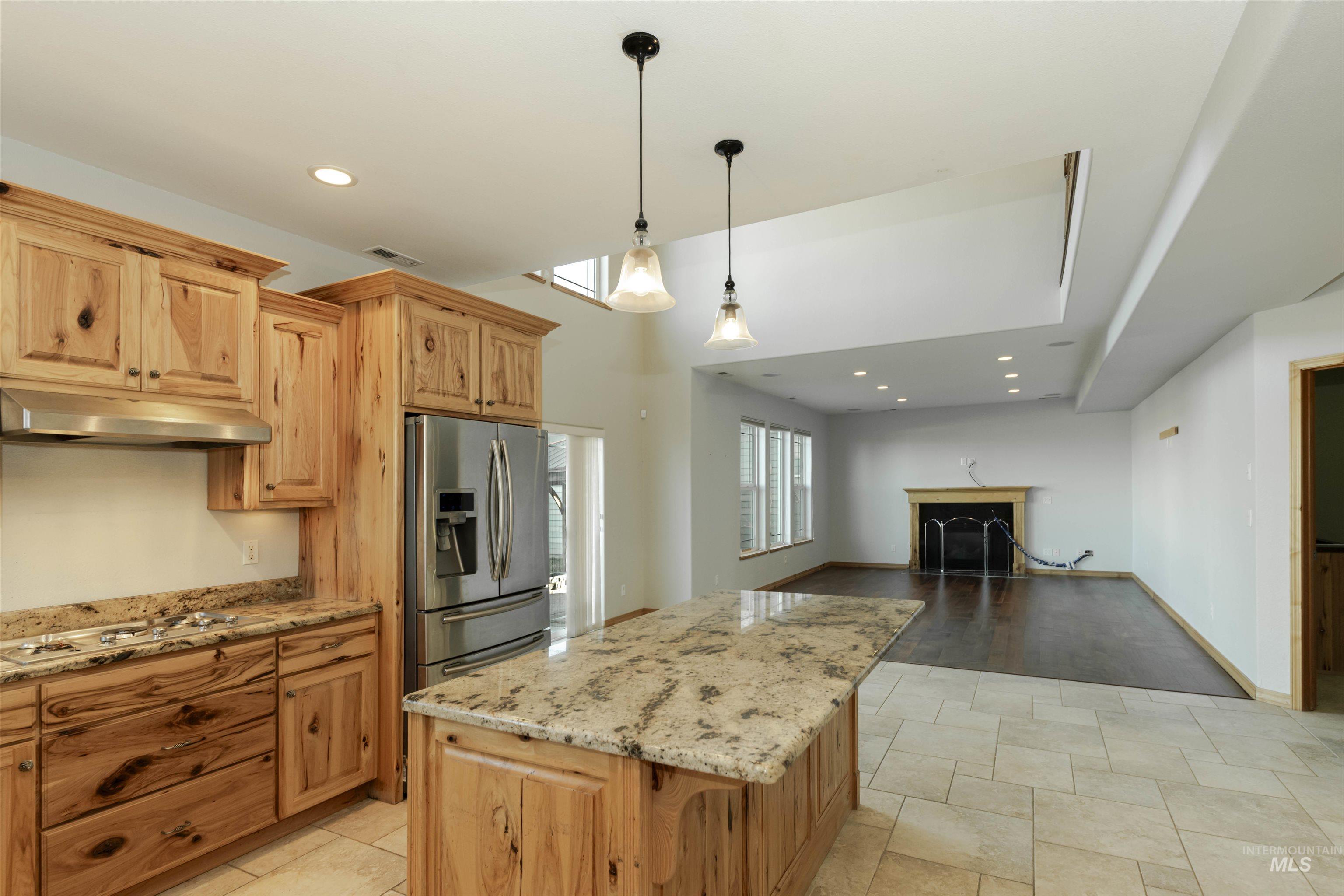 7591 Pheasant Chase Drive Lewiston, ID 83501 - Photo 32 of 32 Kitchen featuring light stone countertops, recessed lighting, stainless steel fridge, hanging light fixtures, and open floor plan
