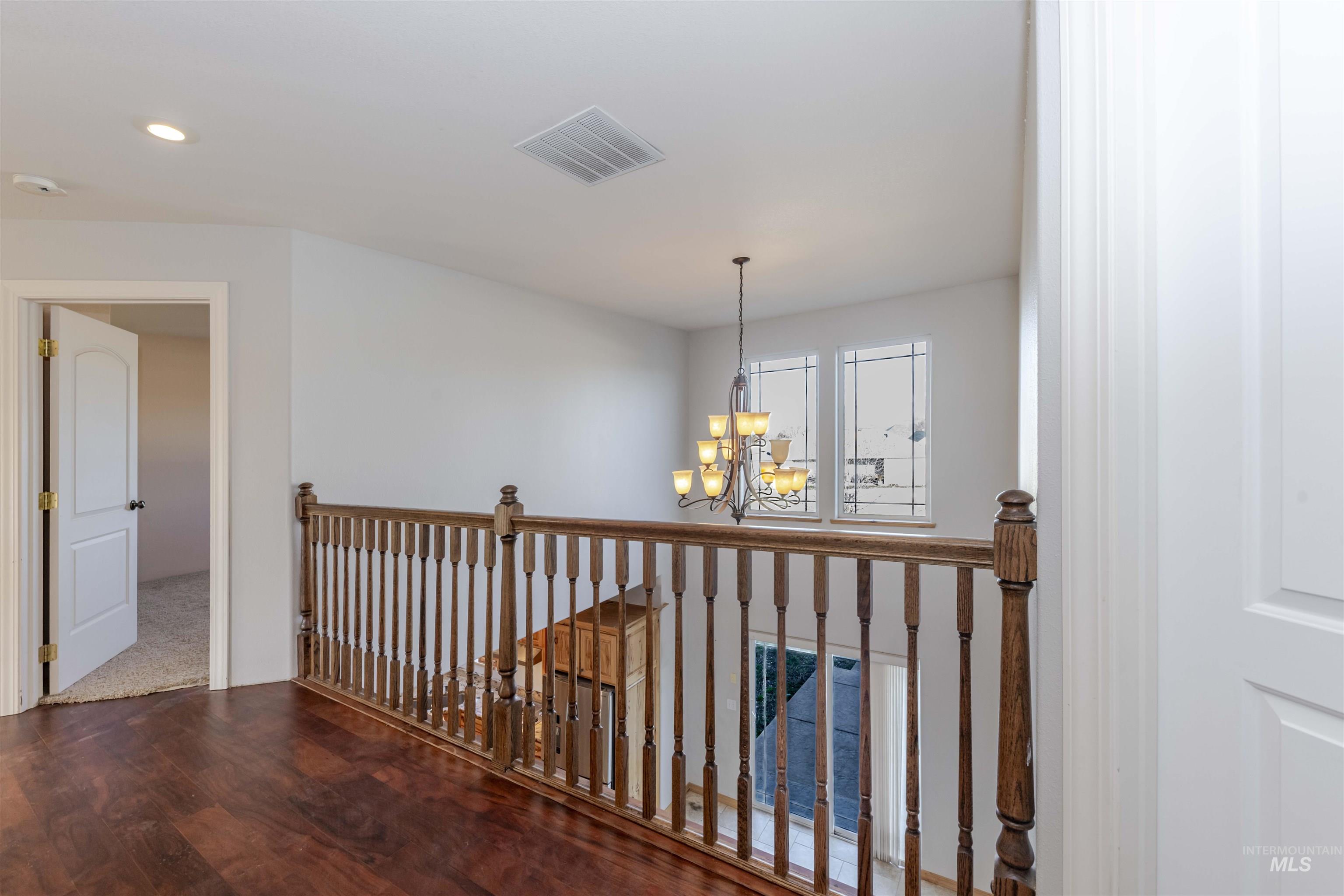 7591 Pheasant Chase Drive Lewiston, ID 83501 - Photo 23 of 32 Corridor featuring a chandelier, dark wood-style floors, and an upstairs landing