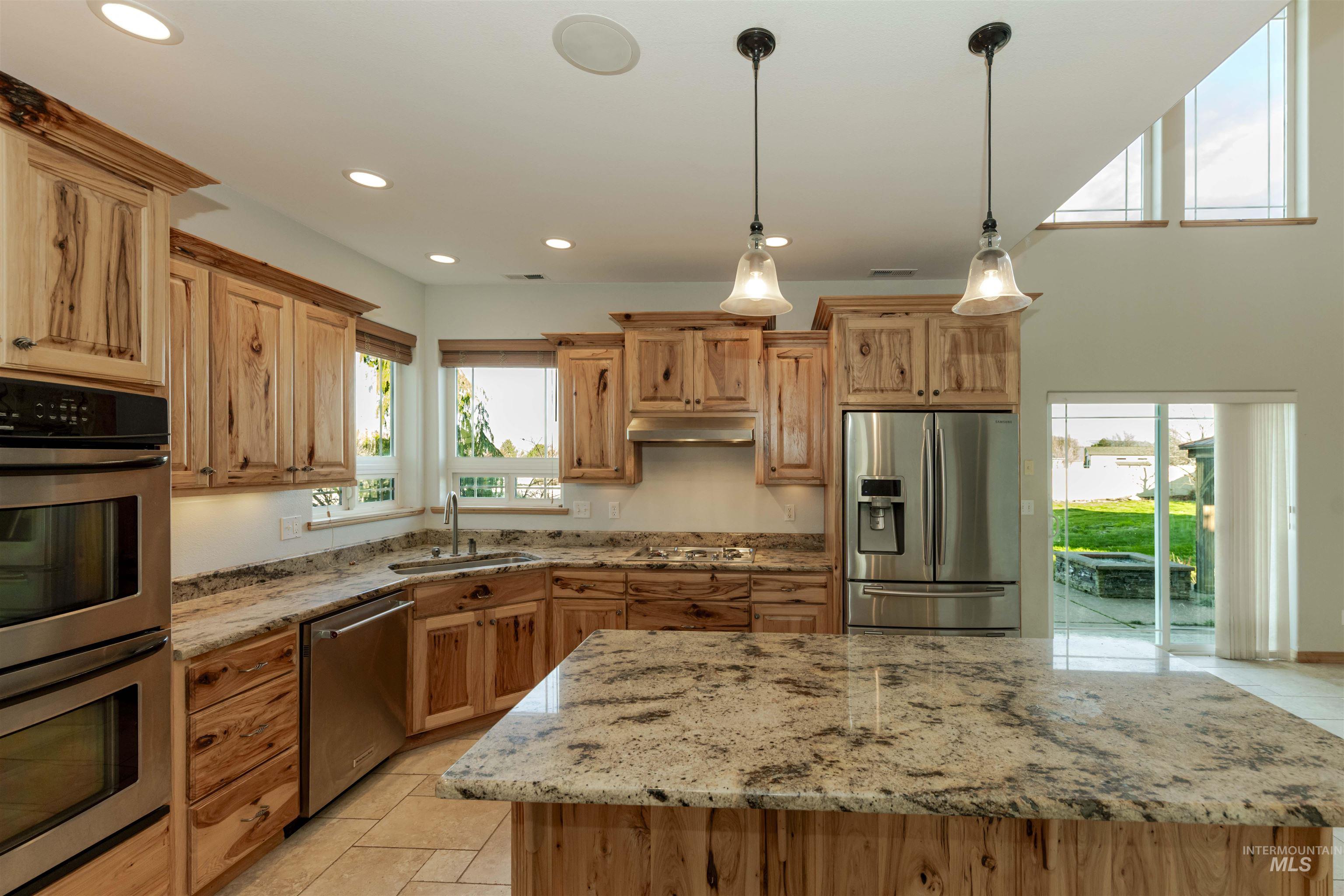 7591 Pheasant Chase Drive Lewiston, ID 83501 - Photo 8 of 32 Kitchen featuring stainless steel appliances, decorative light fixtures, light stone countertops, a kitchen island, and recessed lighting
