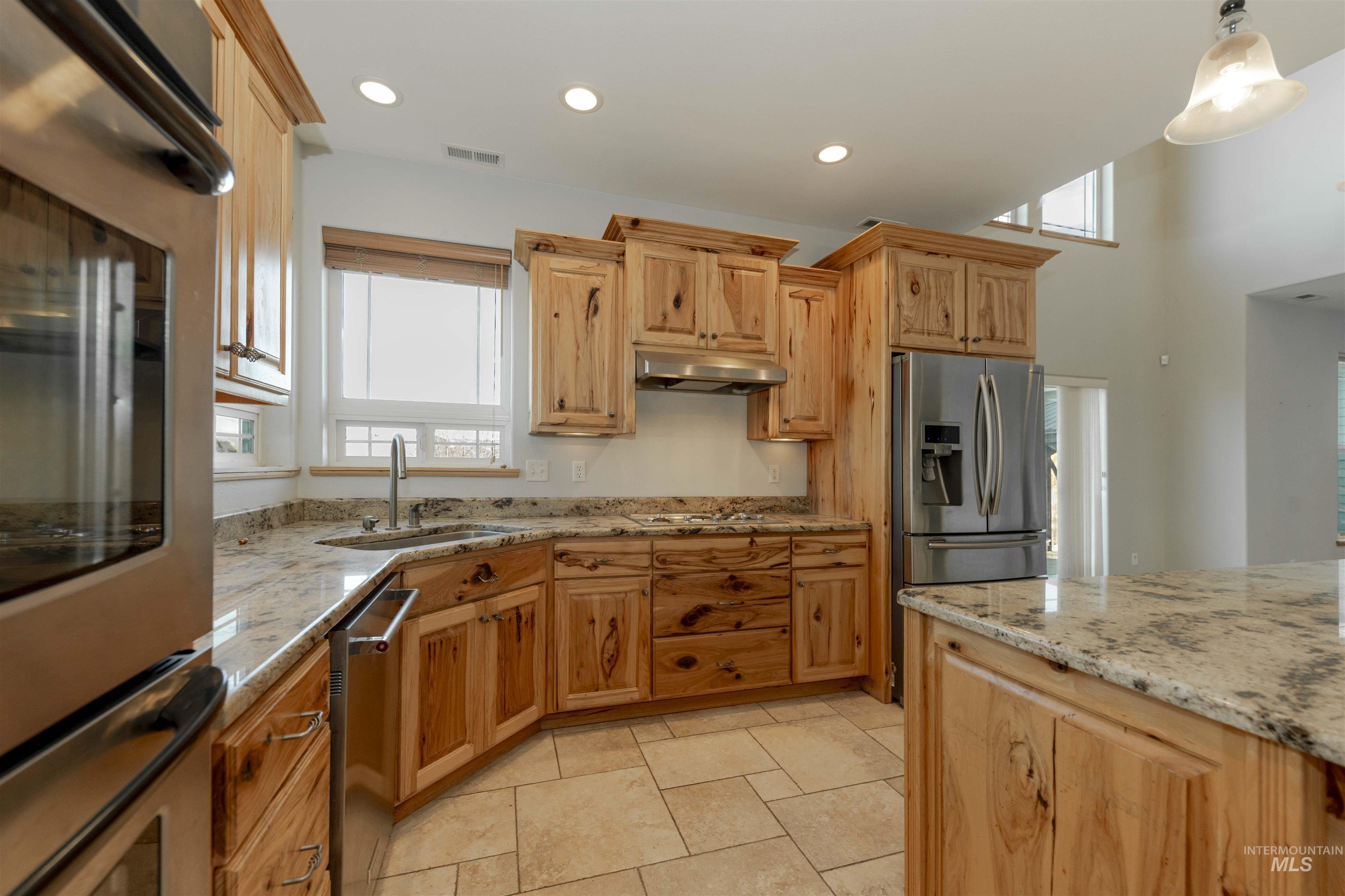 7591 Pheasant Chase Drive Lewiston, ID 83501 - Photo 9 of 32 Kitchen featuring stainless steel appliances, light stone counters, recessed lighting, under cabinet range hood, and decorative light fixtures