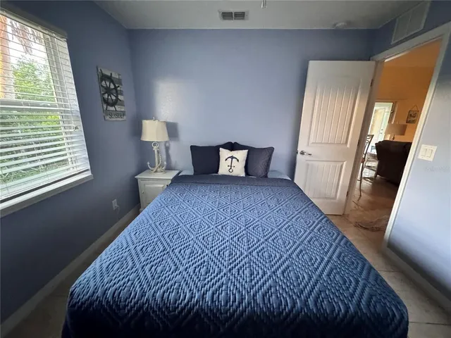 a bedroom with a bed and a large mirror next to a window