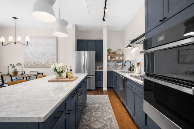 520 West Huron Street, Unit 705 Chicago, IL 60654 - Photo 3 of 14 a kitchen with stainless steel appliances kitchen island granite countertop a table chairs in it and wooden floors