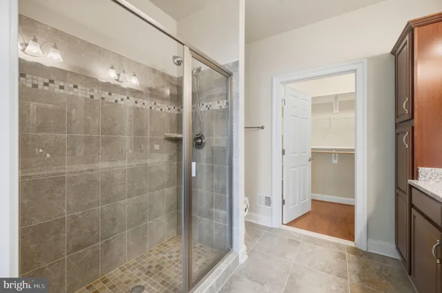 a spacious bathroom with a granite countertop sink a mirror and a shower