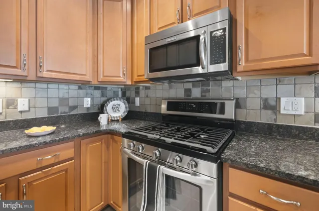 a kitchen with granite countertop stainless steel appliances a stove a sink and dishwasher