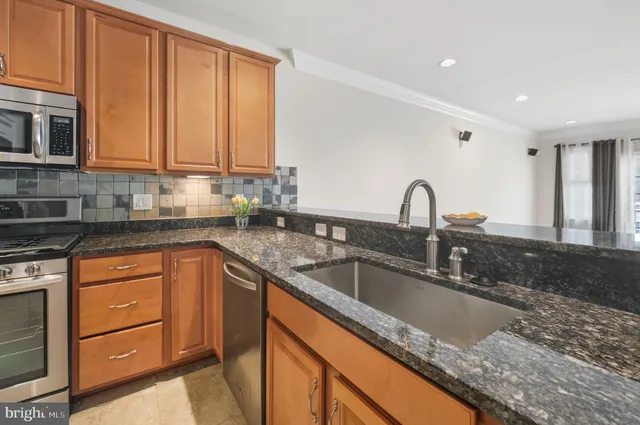 a kitchen with granite countertop a sink stainless steel appliances and cabinets