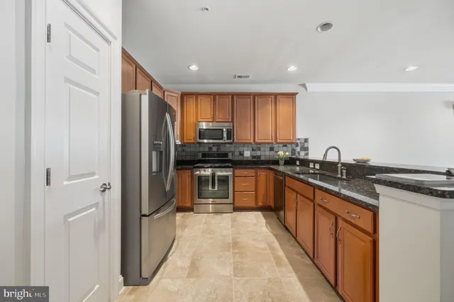 a large kitchen with stainless steel appliances granite countertop a stove a sink and a refrigerator