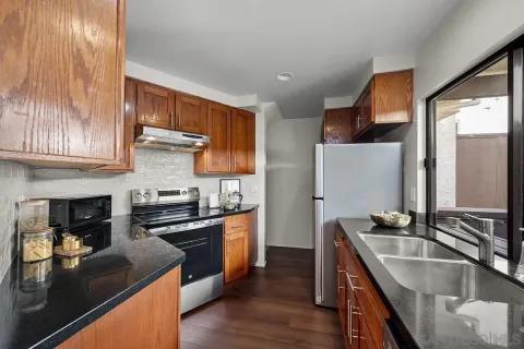 a kitchen with stainless steel appliances granite countertop a sink a stove and a refrigerator