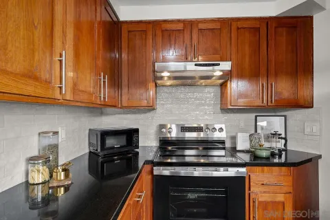 a kitchen with granite countertop wood cabinets stainless steel appliances and a sink
