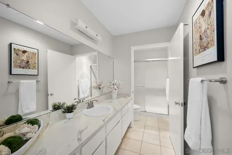 a bathroom with a granite countertop sink a mirror a bathtub and shower