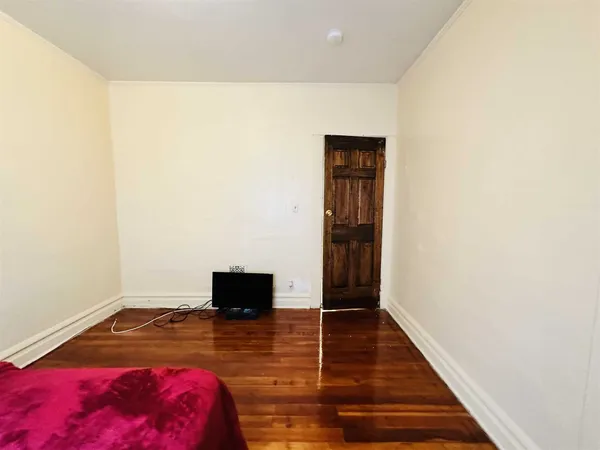 a living room with a bed and a wooden floor