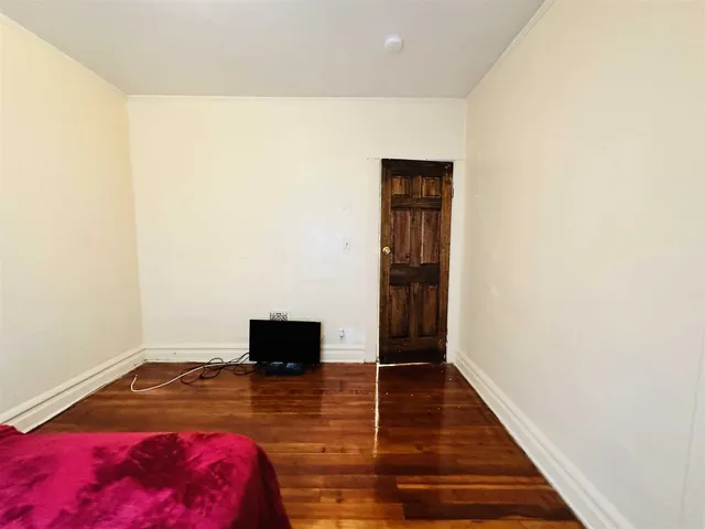 a living room with a bed and a wooden floor