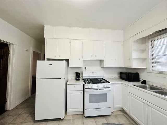 a kitchen with refrigerator a stove a white sink and cabinets