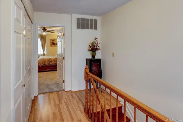 a view of a hallway to a livingroom with wooden floor and stairs