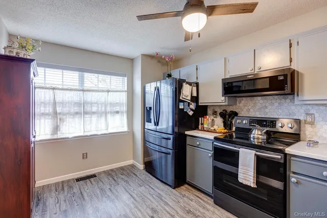 a kitchen with granite countertop a refrigerator and a stove top oven
