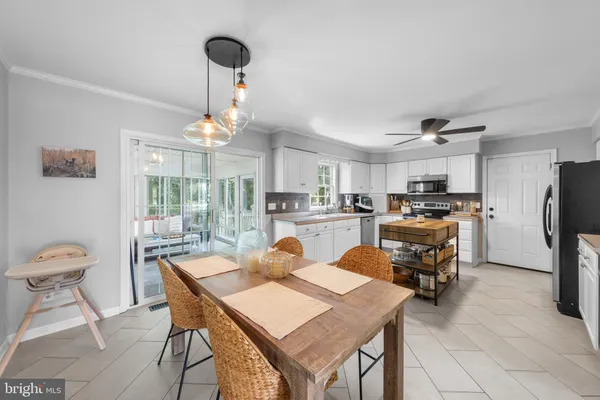 a kitchen with stainless steel appliances granite countertop a stove a refrigerator a kitchen island a table and chairs