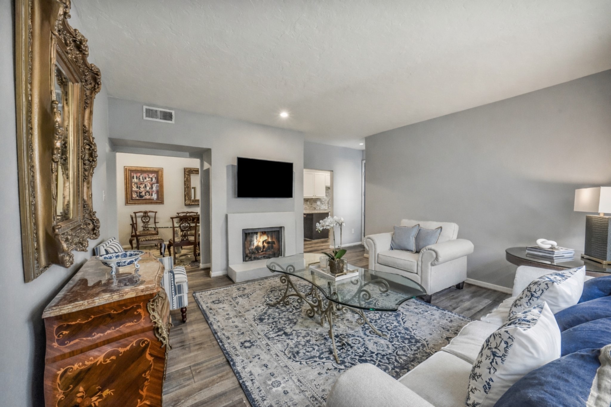 2100 Tanglewilde Street, Unit 591 Houston, TX 77063 - Photo 3 of 18 Another view of the spacious family room with a wood-burning fireplace, creating a warm focal point and comfortable gathering space. The open layout flows seamlessly into the dining and kitchen areas — ideal for everyday living and entertaining. Dining is to the right of the fireplace and kitchen is to the left of the fireplace.