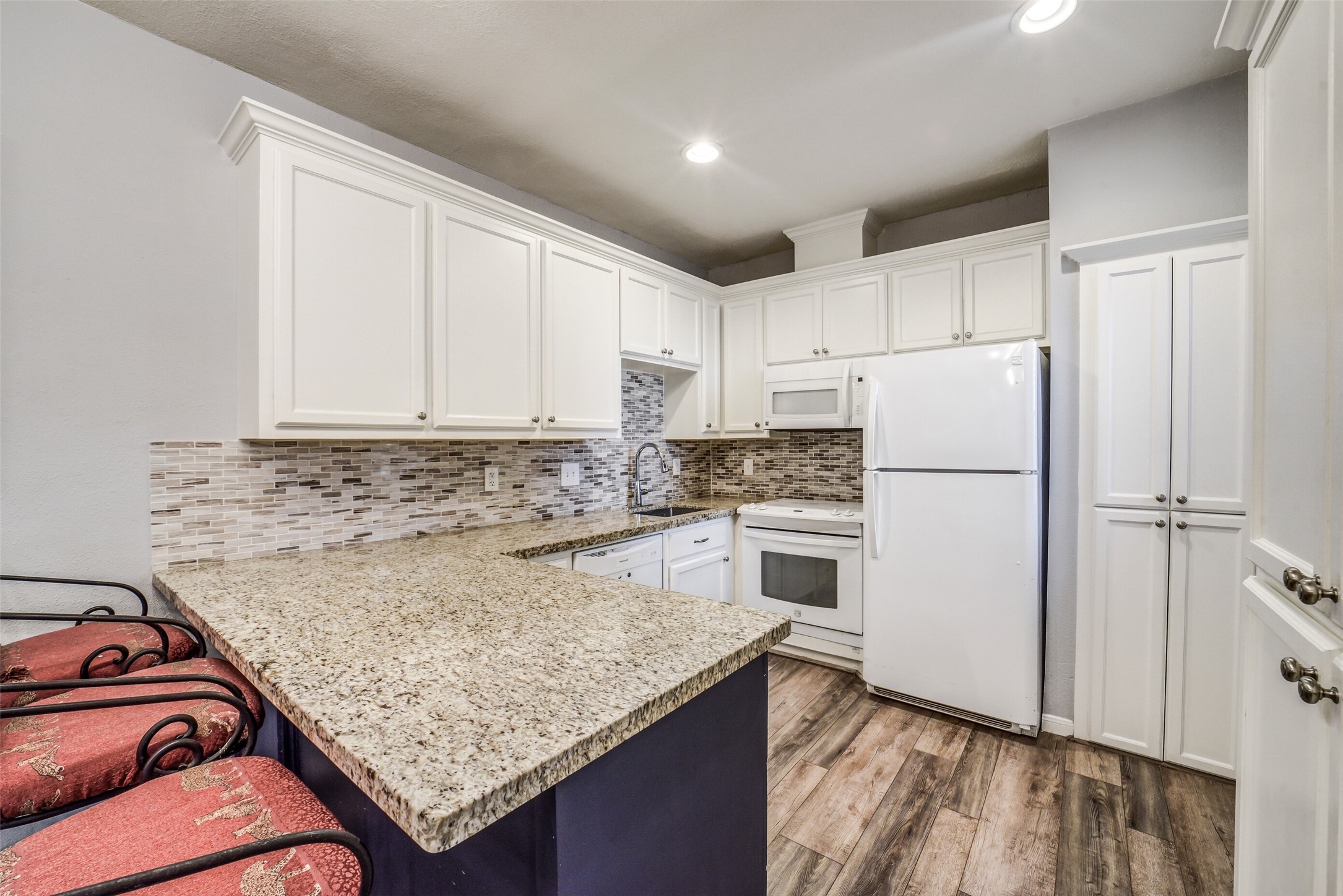 2100 Tanglewilde Street, Unit 591 Houston, TX 77063 - Photo 7 of 18 Wonderful updated kitchen features granite countertops, decorative tile backsplash, breakfast bar seating, and abundant cabinetry for storage. A functional layout designed for both daily convenience and entertaining. Refrigerator included.