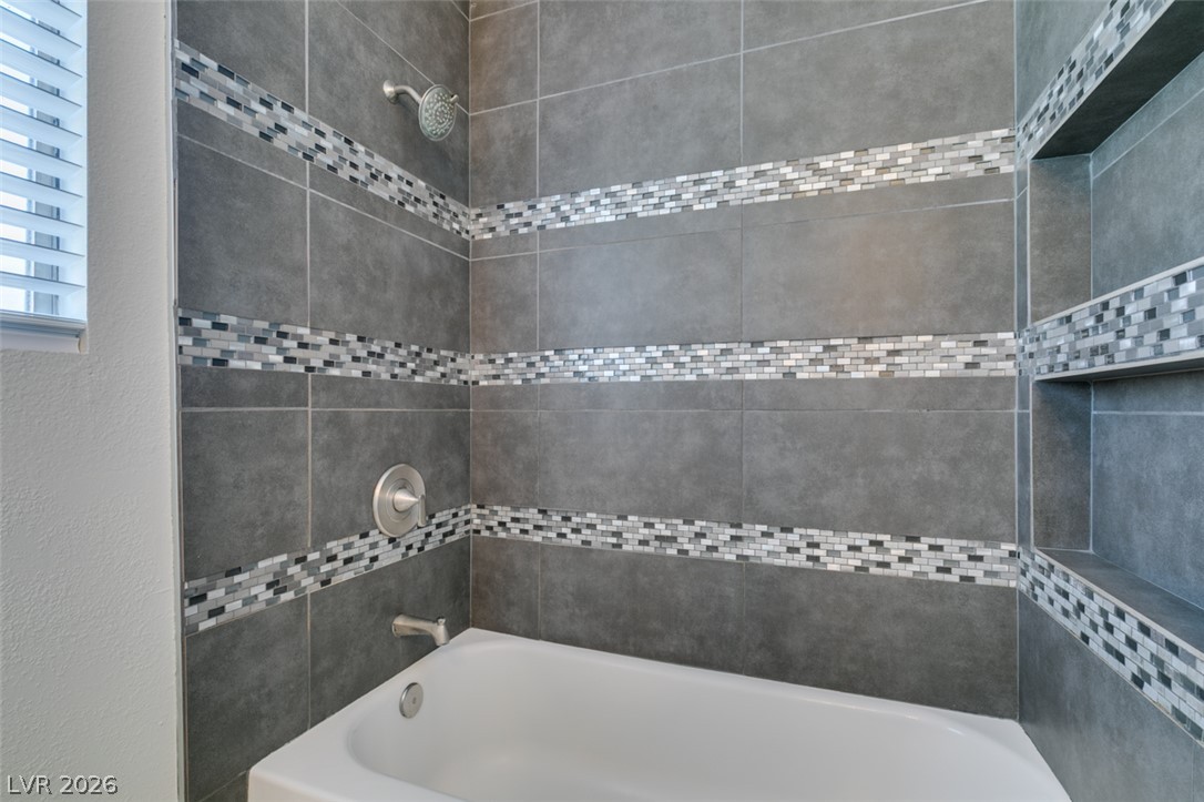 2028 Rustler Ridge Avenue North Las Vegas, NV 89031 - Photo 28 of 40 A sleek shower and tub combination featuring contemporary gray tile and mosaic accents.