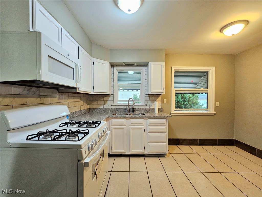 13514 Granger Road Cleveland, OH 44125 - Photo 6 of 23 Kitchen with light stone countertops, sink, white appliances, and white cabinetry